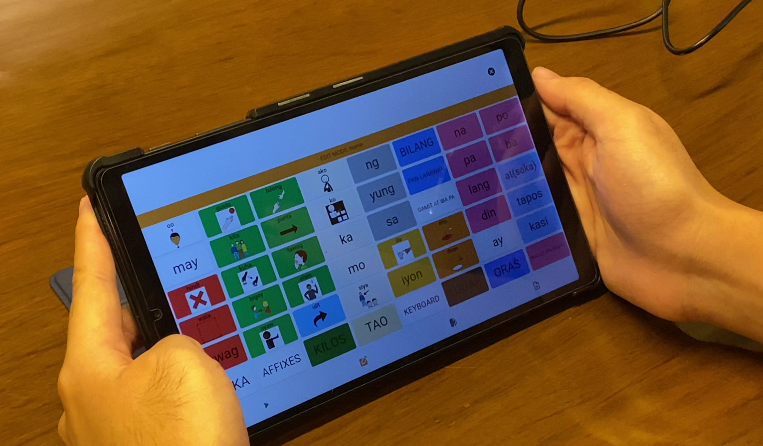 Child using AAC communication board with teacher